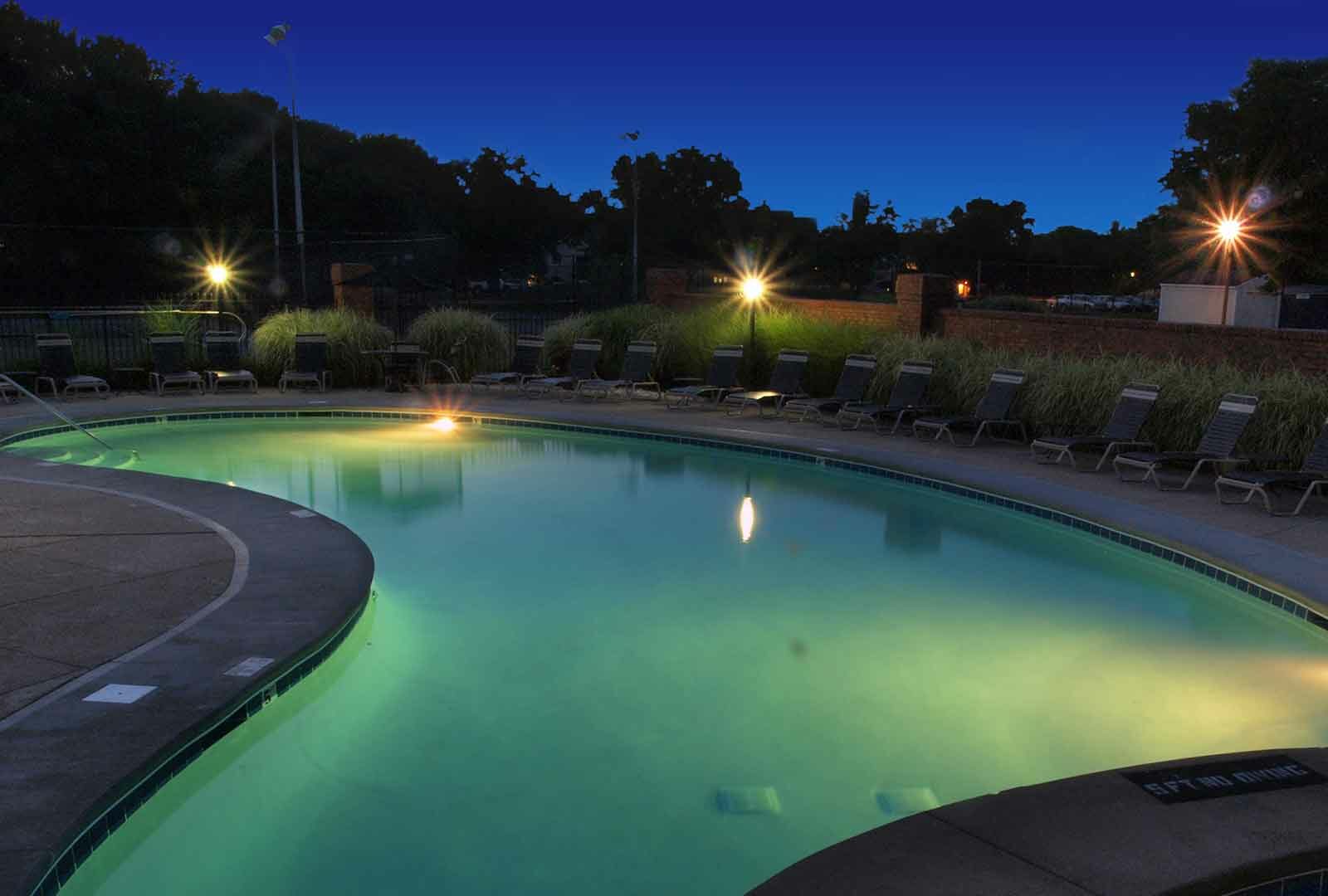 Outdoor pool with night lighting and lounge deck at Fox Chase North.