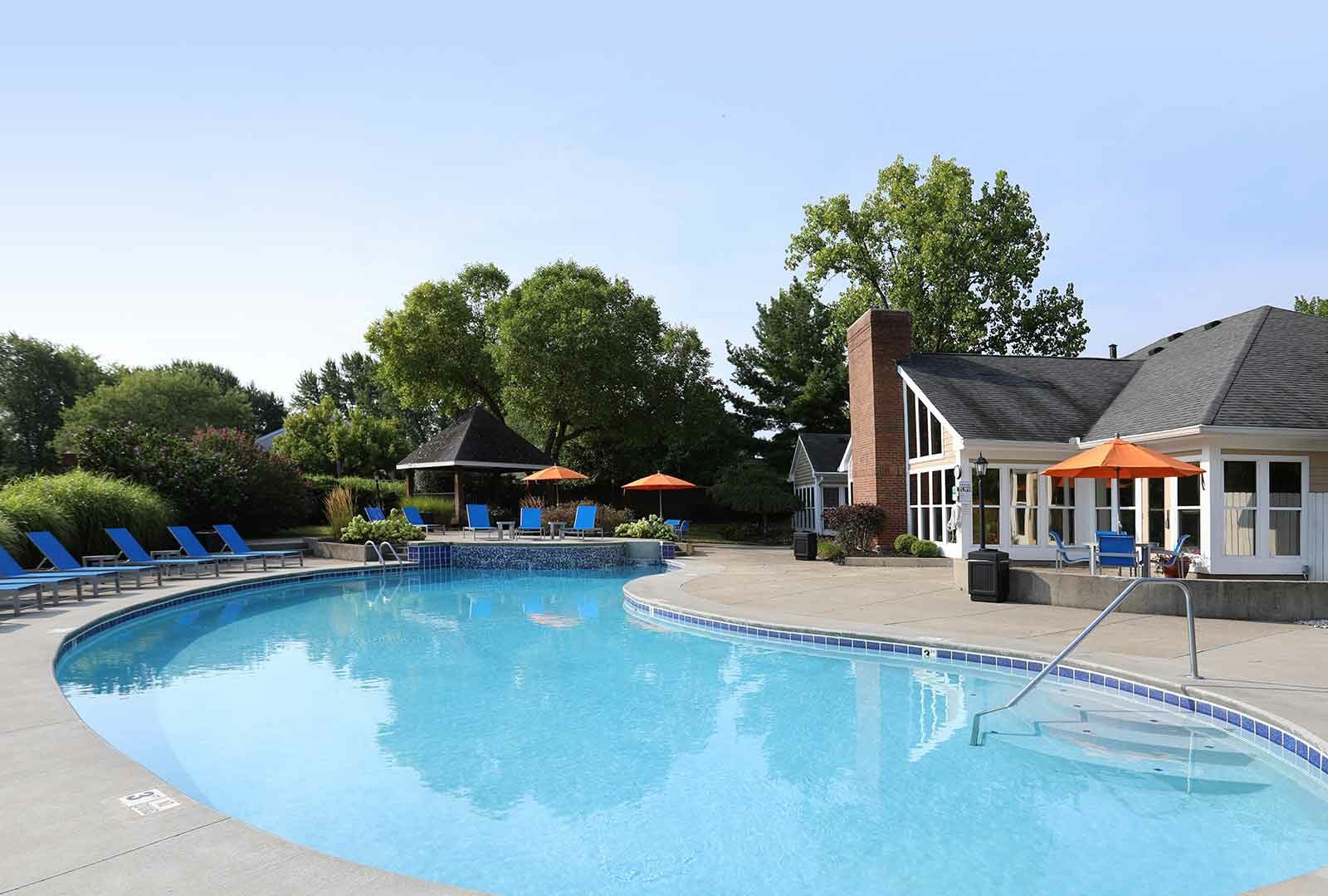 Community swimming pool and hot tub surrounded by lounge chairs.