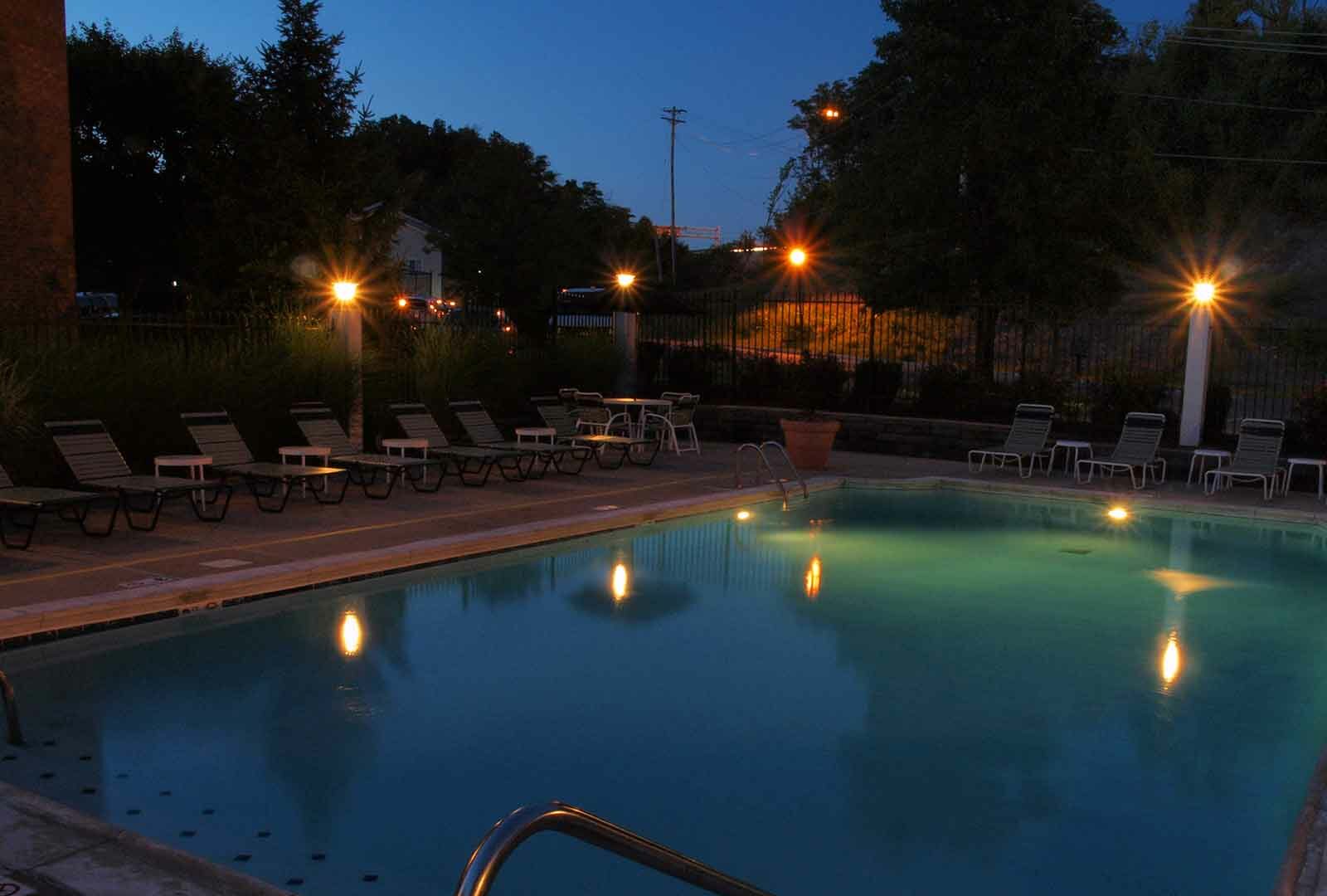 Outdoor pool with night lighting and lounge deck at Fox Chase South.