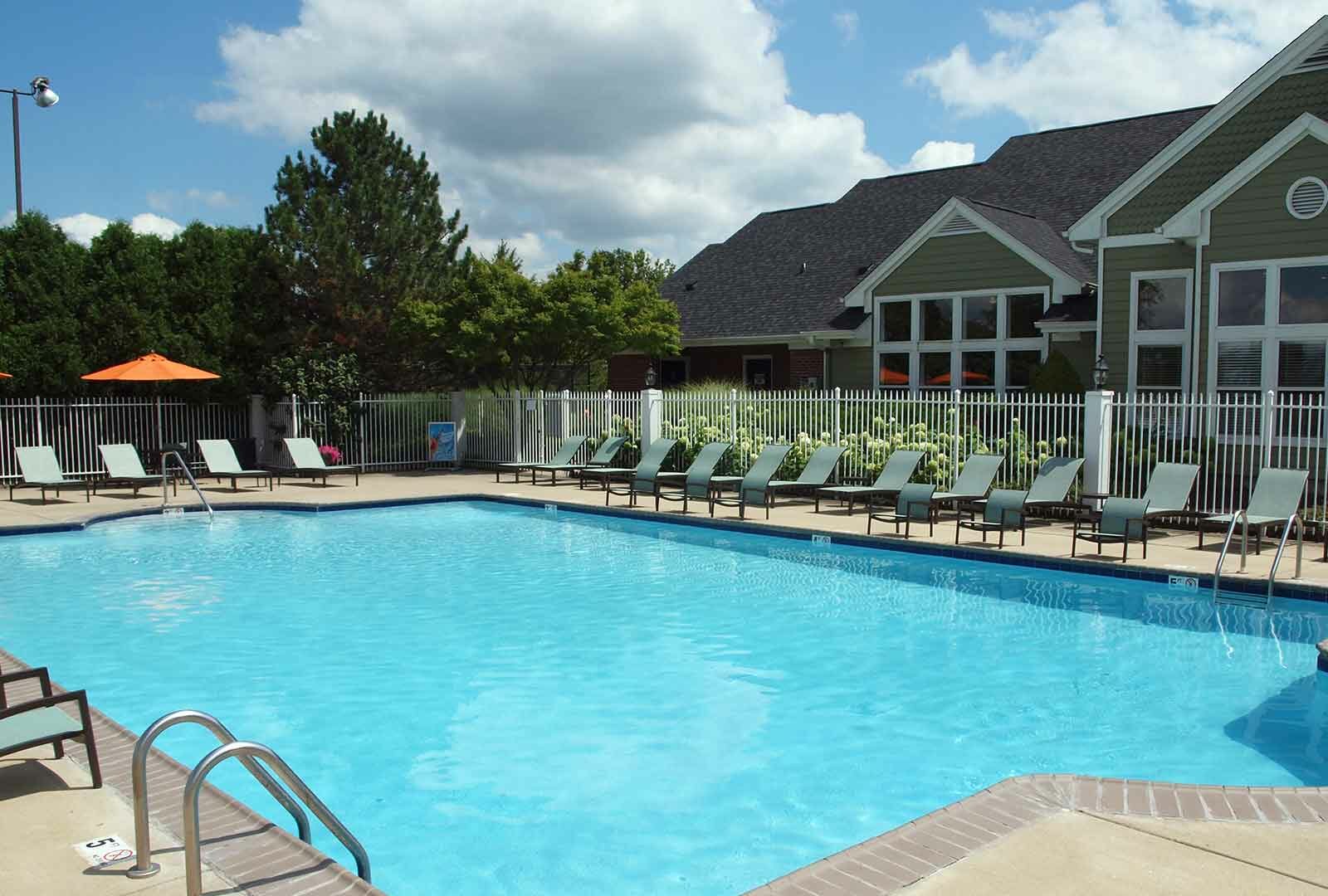 Outdoor pool and lounge chairs next to Wellington Place clubhouse.