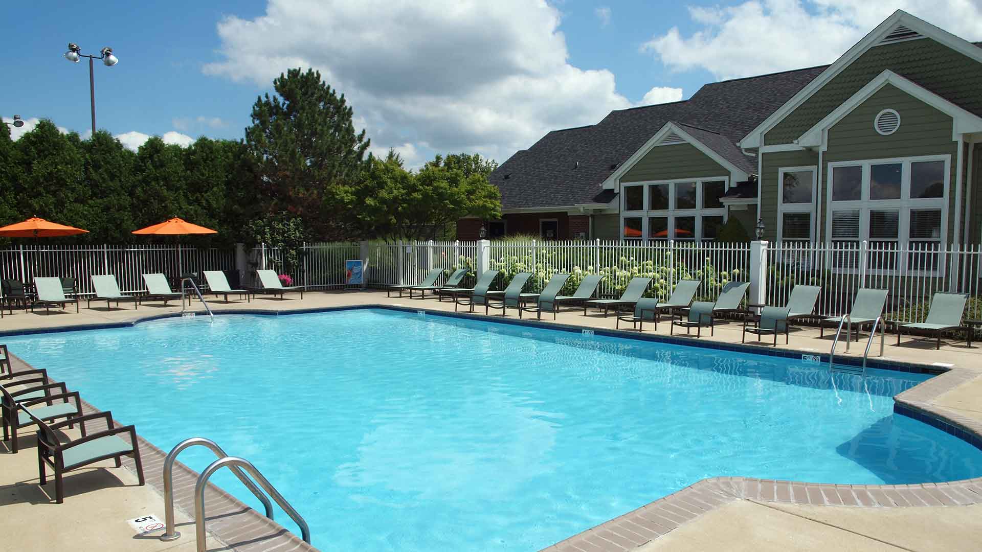 Outdoor pool and lounge chairs next to Wellington Place clubhouse.