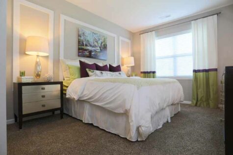 Carpeted bedroom furnished with nightstands and large bed.