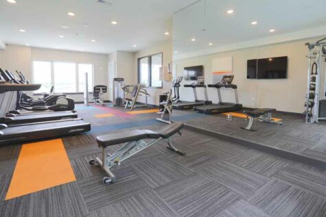 Fitness room equipped with workout machines and television.