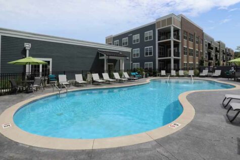 Apartment pool furnished with lounge chairs.