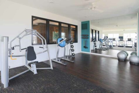 Community fitness center with exercise machines and mirrors.