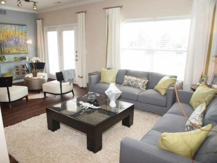 Open living space with large windows, sofas, chairs, and decor.