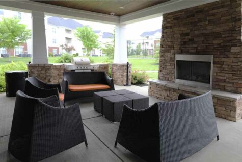 Large covered patio with fireplace, furniture, and gas grill.