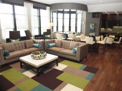 Furnished clubhouse with sofas and multiple 4-person tables.