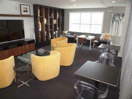 Resident café with a TV, lounge seating, and tables.