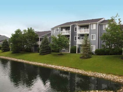 Exterior of Sterling Lakes apartment building next to a small lake.