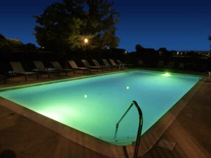 Outdoor pool with night lighting and lounge deck with chairs at Wellington Place.