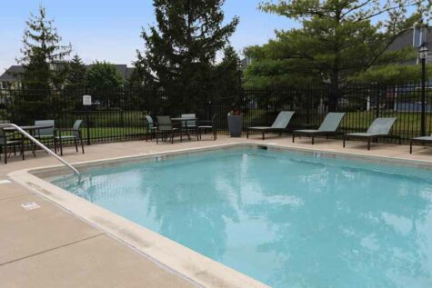 Outdoor pool and lounge deck with chairs and tables at Wellington Place.
