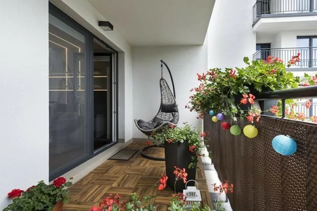 An apartment balcony with a hammock chair.