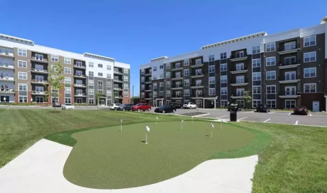 A small golf putting range overlooked by large, new apartments.