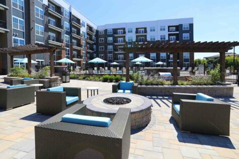 An outdoor firepit and lounge area immediately outside of a large apartment building.