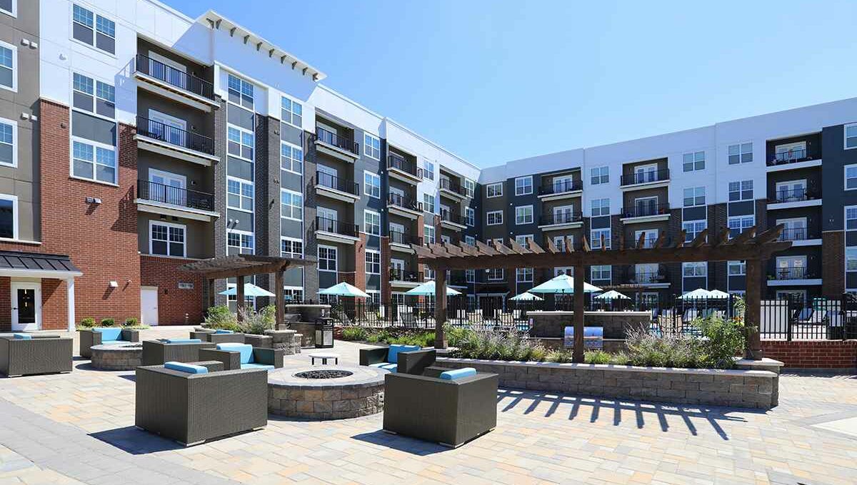 An outdoor firepit and lounge area immediately outside of a large apartment building.