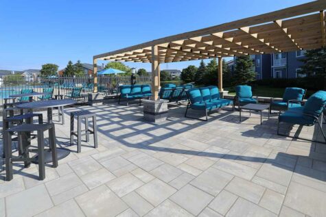 A large outdoor patio and social deck with a pool in the background.