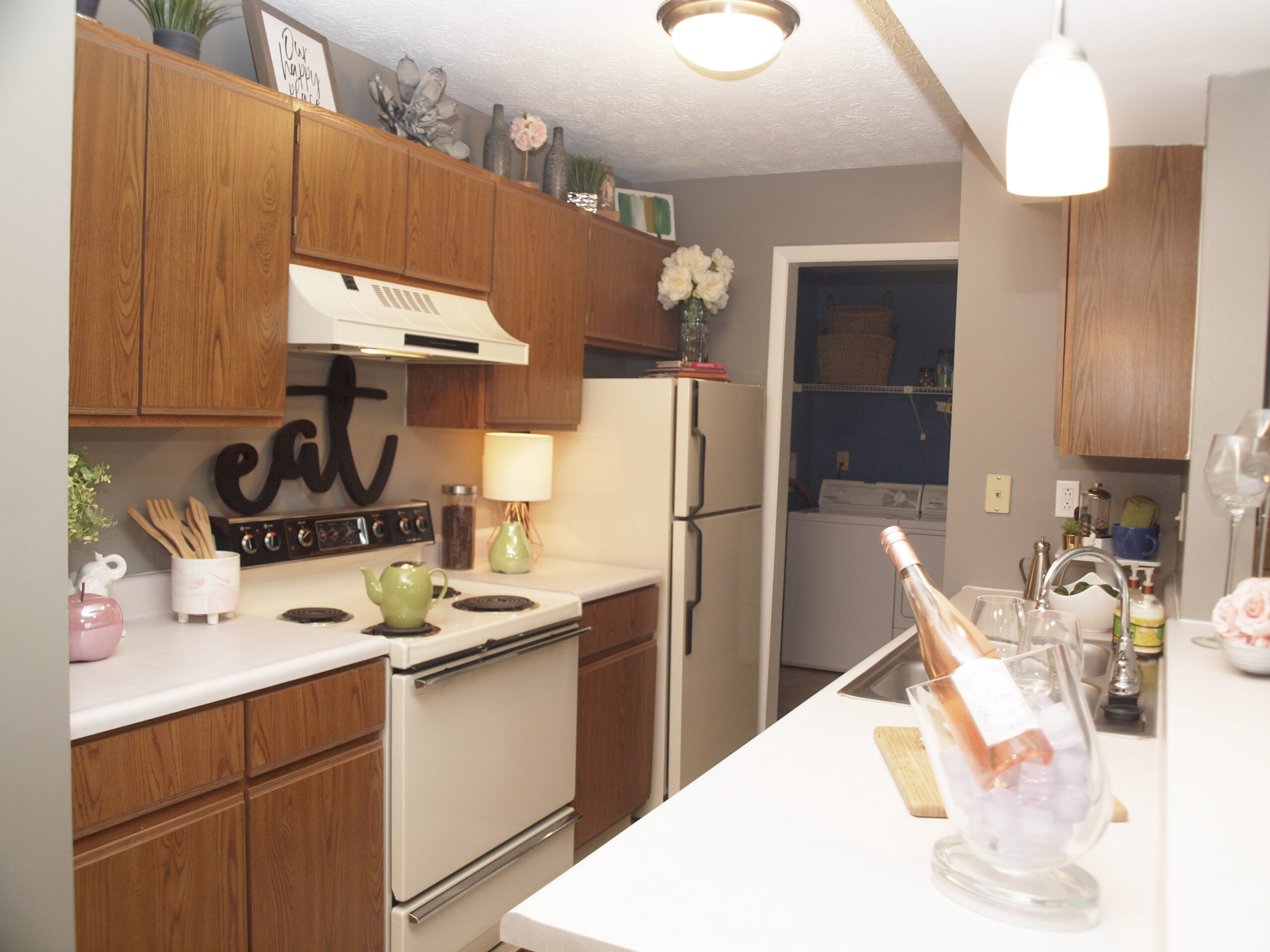 An alley kitchen with dark walnut cabinets and white appliances.
