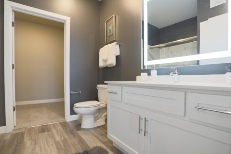 A clean and modern bathroom featuring a large, self-illuminated mirror.