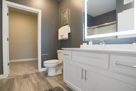 A clean and modern bathroom featuring a large, self-illuminated mirror.