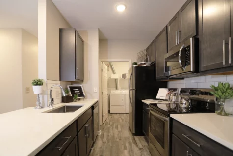 Chef-ready kitchen with dark walnut cabinets and stainless steel appliances connected to in-unit laundry