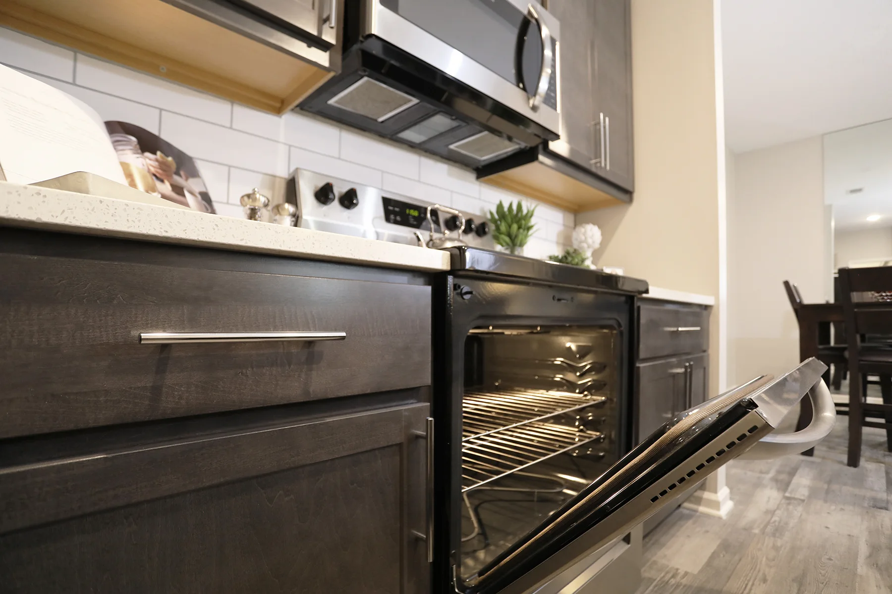 A clean, stainless steel oven slightly ajar sits under a matching, wall-mounted microwave.