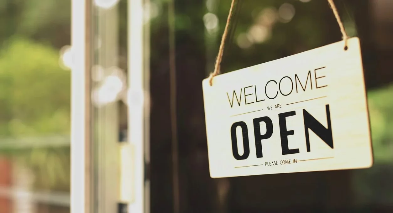 A welcome or open sign hanging on the front door of a business. 