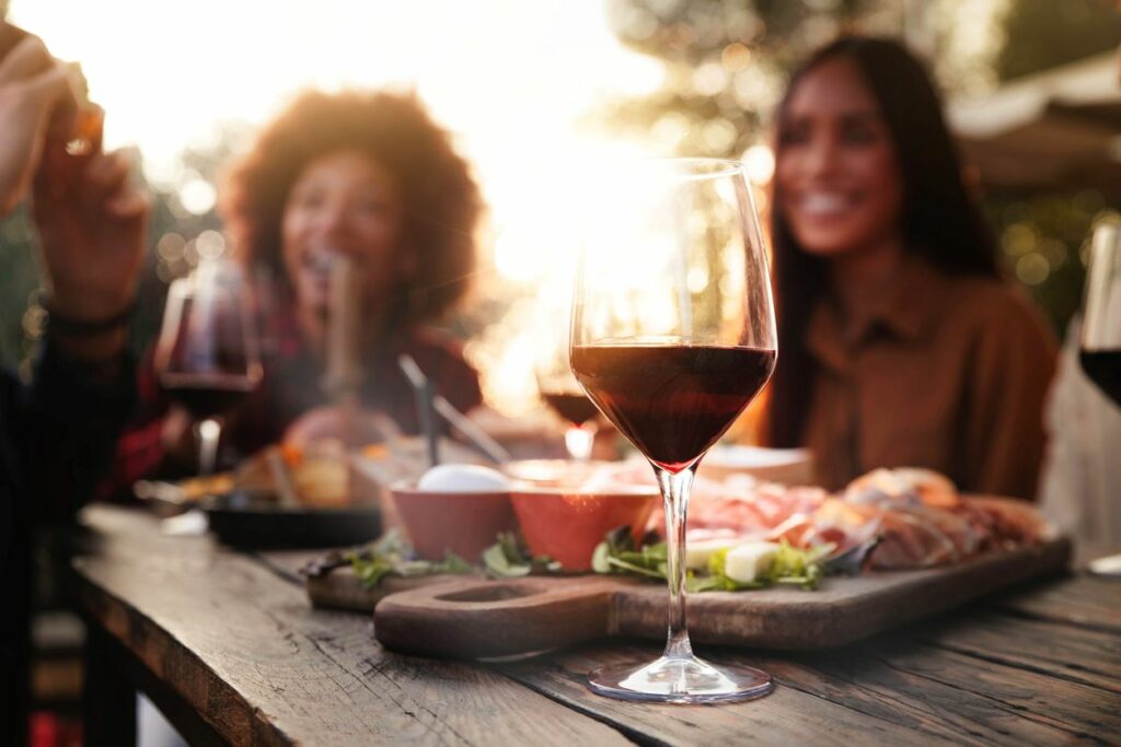 A group of people eating outside at a restaurant with a wine glass and appetizer. 