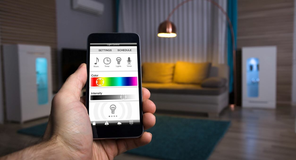 A phone with a smart light in a lamp in the background of the living room
