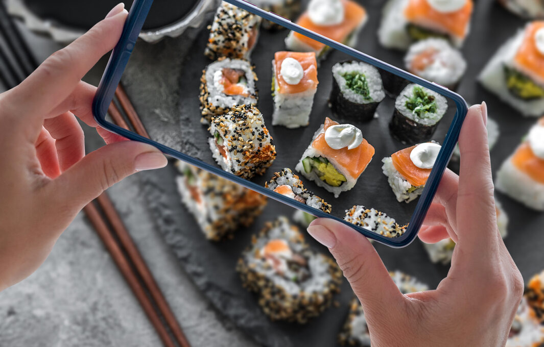 A phone capturing a picture of a delicious sushi meal.