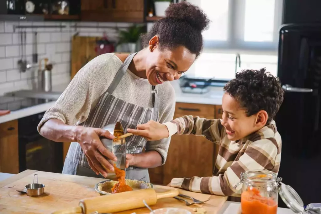 Mom and son prepare a pumpkin pie with autumn decorations in the background