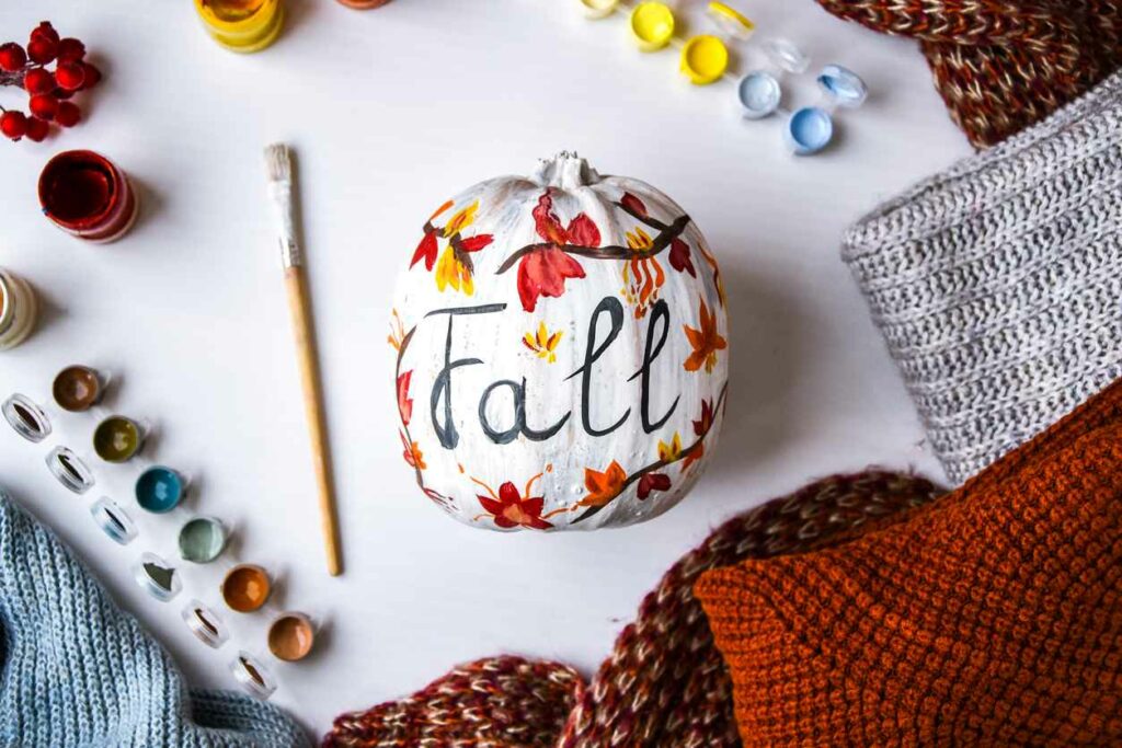 A pumpkin that's painted with the word "fall" on it.