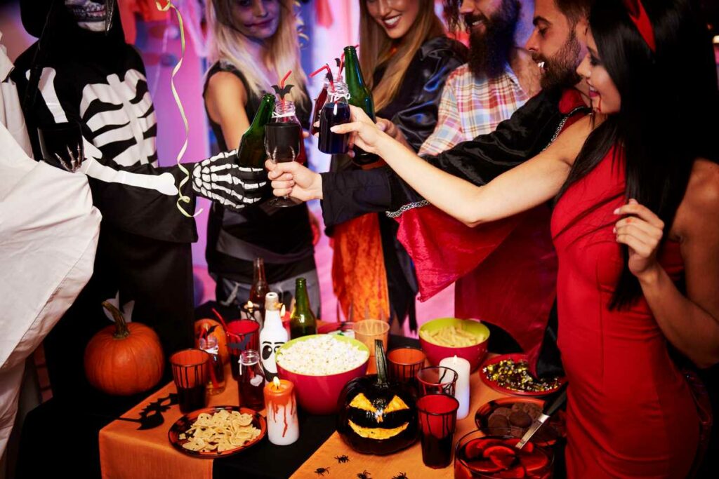 Friends in costumes toast with champagne flutes while having a Halloween party