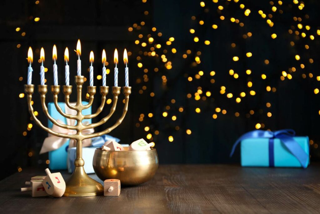 A lit menorah with lights lining the background