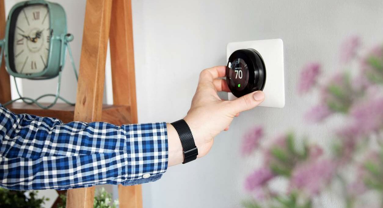 A homeowner adjusts the thermostat to 70 degrees to save on energy bills.