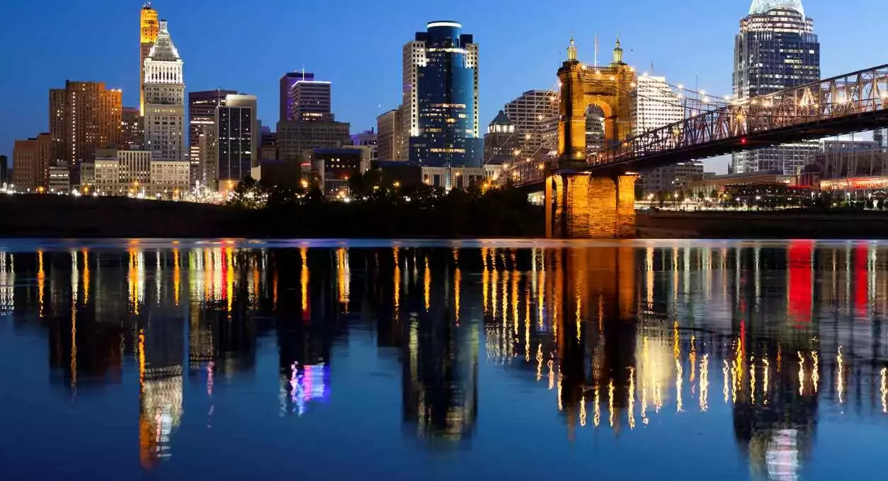 The Cincinnati skyline sparkles at sunrise, with the John A. Roebling Suspension Bridge glowing in the foreground.