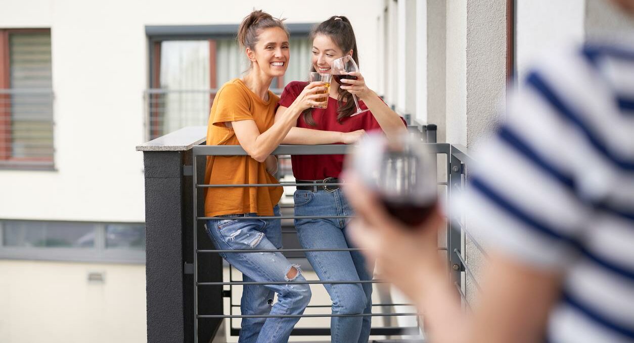 2 women on a balcony talking to their neighbors