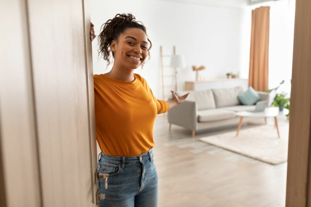 A smiling young woman welcomes visitors inside.