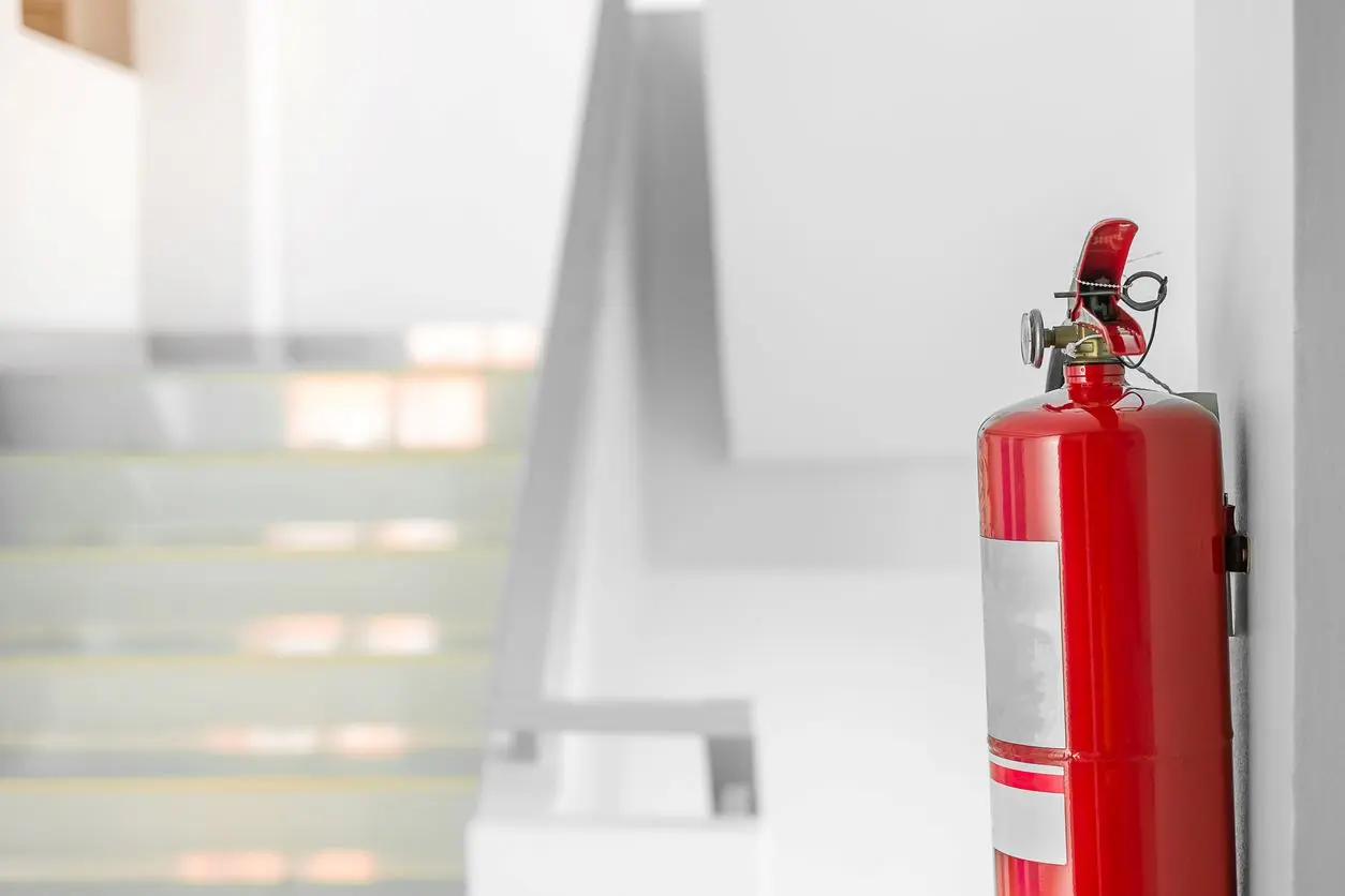 A side view of a fire extinguisher hanging on a wall in a stairwell.