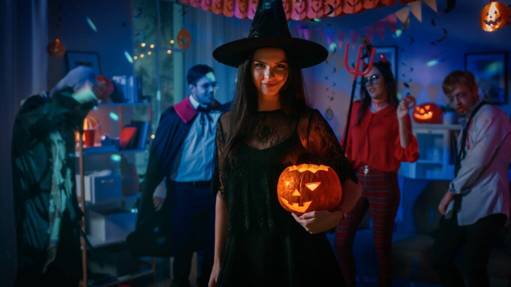 A young woman decorates for Halloween by drawing a face on a pumpkin.