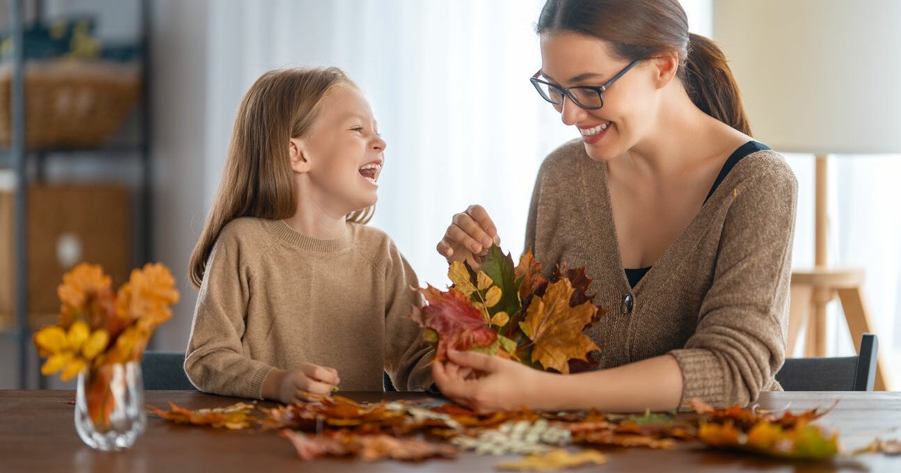 A happy mother and daughter organize fall leaves for DIY crafts.