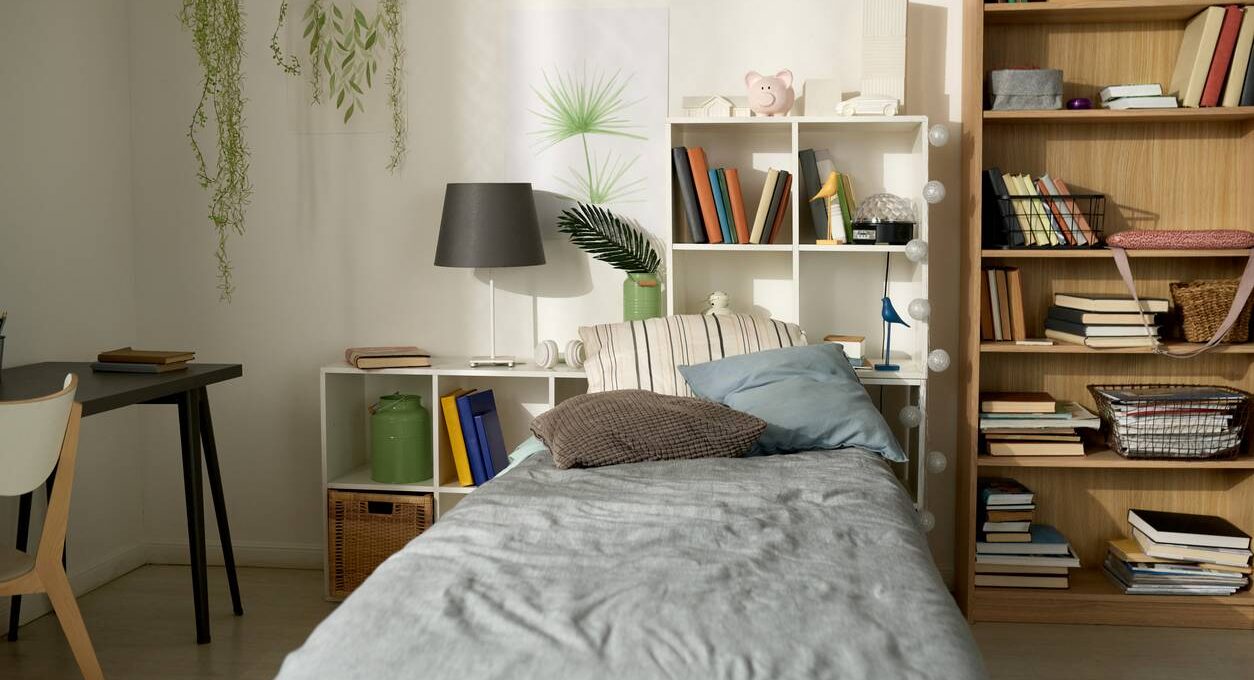 A bed layered with bedding is surrounded by green plants.