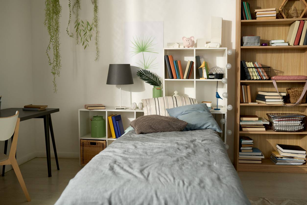 A bed layered with bedding is surrounded by green plants.