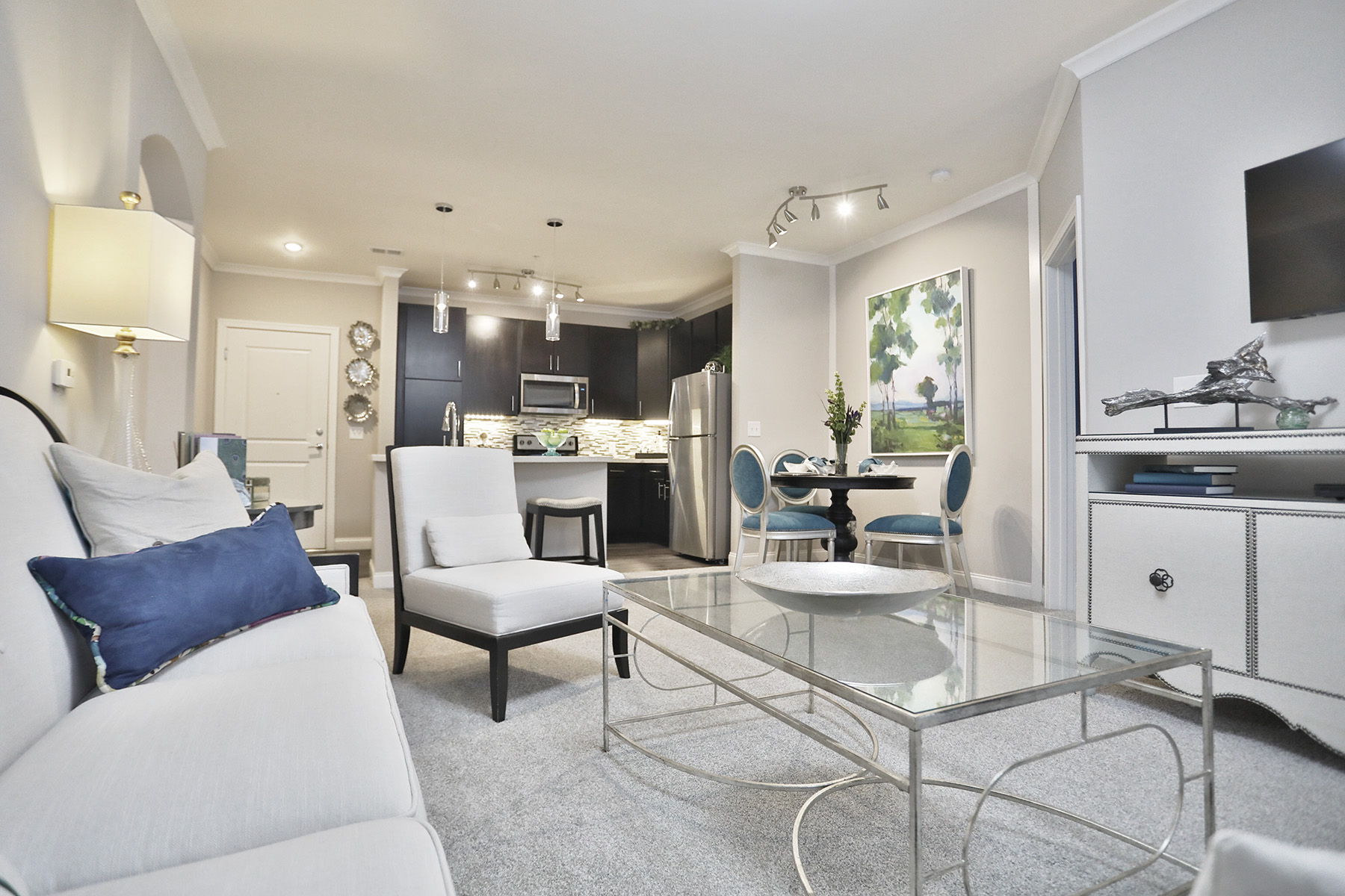 Living room view of a two-bedroom home at 49Hundred Apartments featuring large windows, modern finishes, and an open layout that flows seamlessly into the kitchen and dining areas.