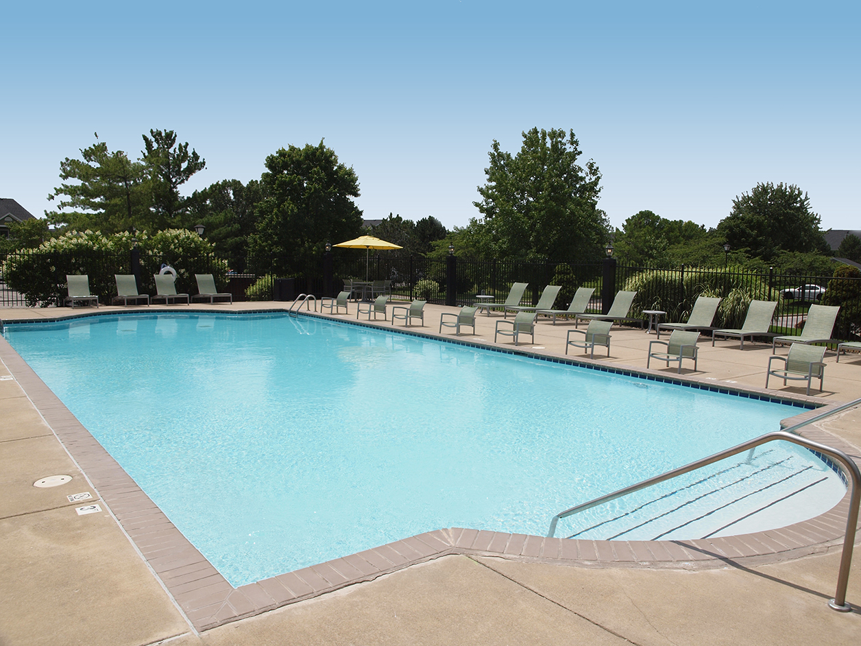 Swimming pool at Emerald Lakes Apartments featuring crystal-clear water, surrounding lounge chairs, and a landscaped setting perfect for relaxation and outdoor enjoyment.
