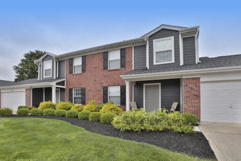 Exterior view of a townhome at Wellington Place Apartments showcasing updated finishes, private entry, attached garage, and well-maintained landscaping.