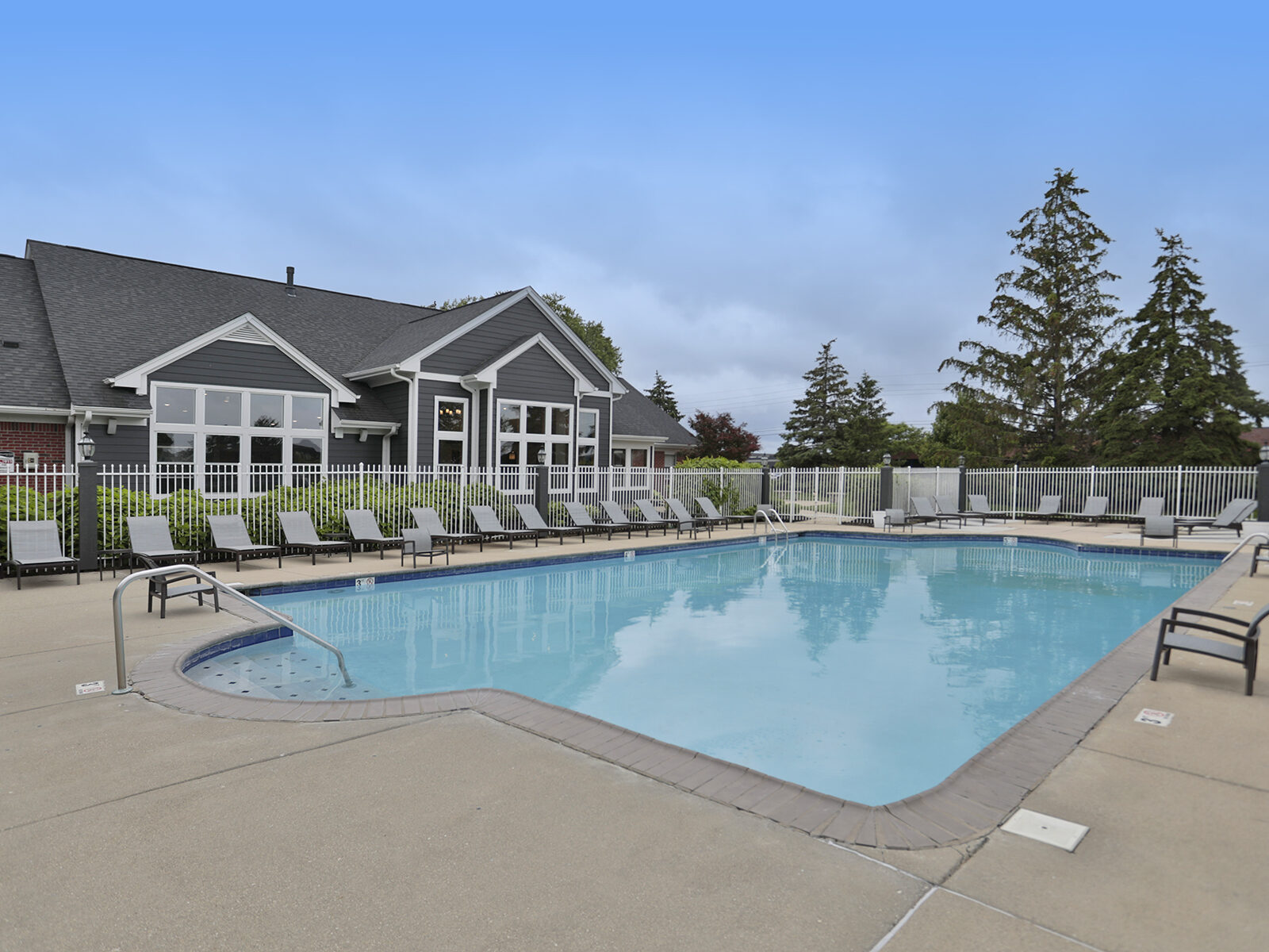 Resort-style swimming pool at Wellington Place Apartments in Fishers, IN, featuring lounge chairs, clear blue water, and a beautifully landscaped setting.