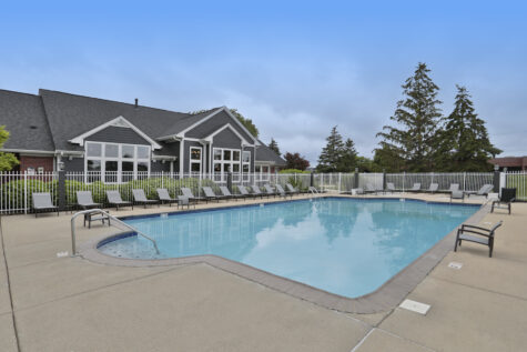 Resort-style swimming pool at Wellington Place Apartments in Fishers, IN, featuring lounge chairs, clear blue water, and a beautifully landscaped setting.