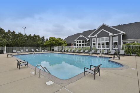 Resort-style swimming pool at Wellington Place Apartments in Fishers, IN, featuring lounge chairs, clear blue water, and a beautifully landscaped setting.