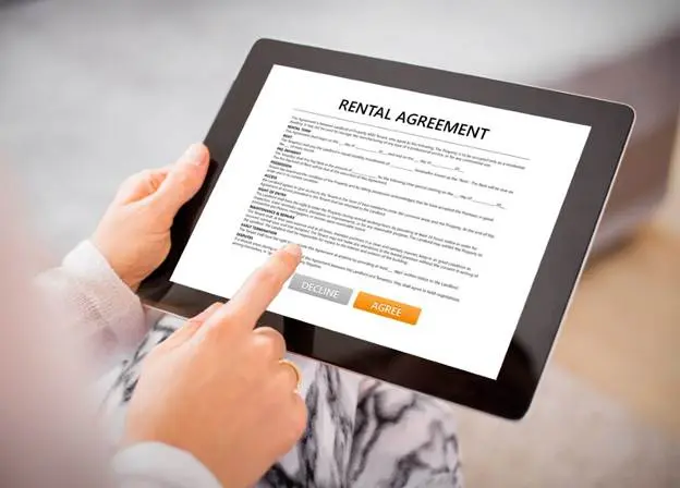 A person uses a tablet to read and sign a rental application.